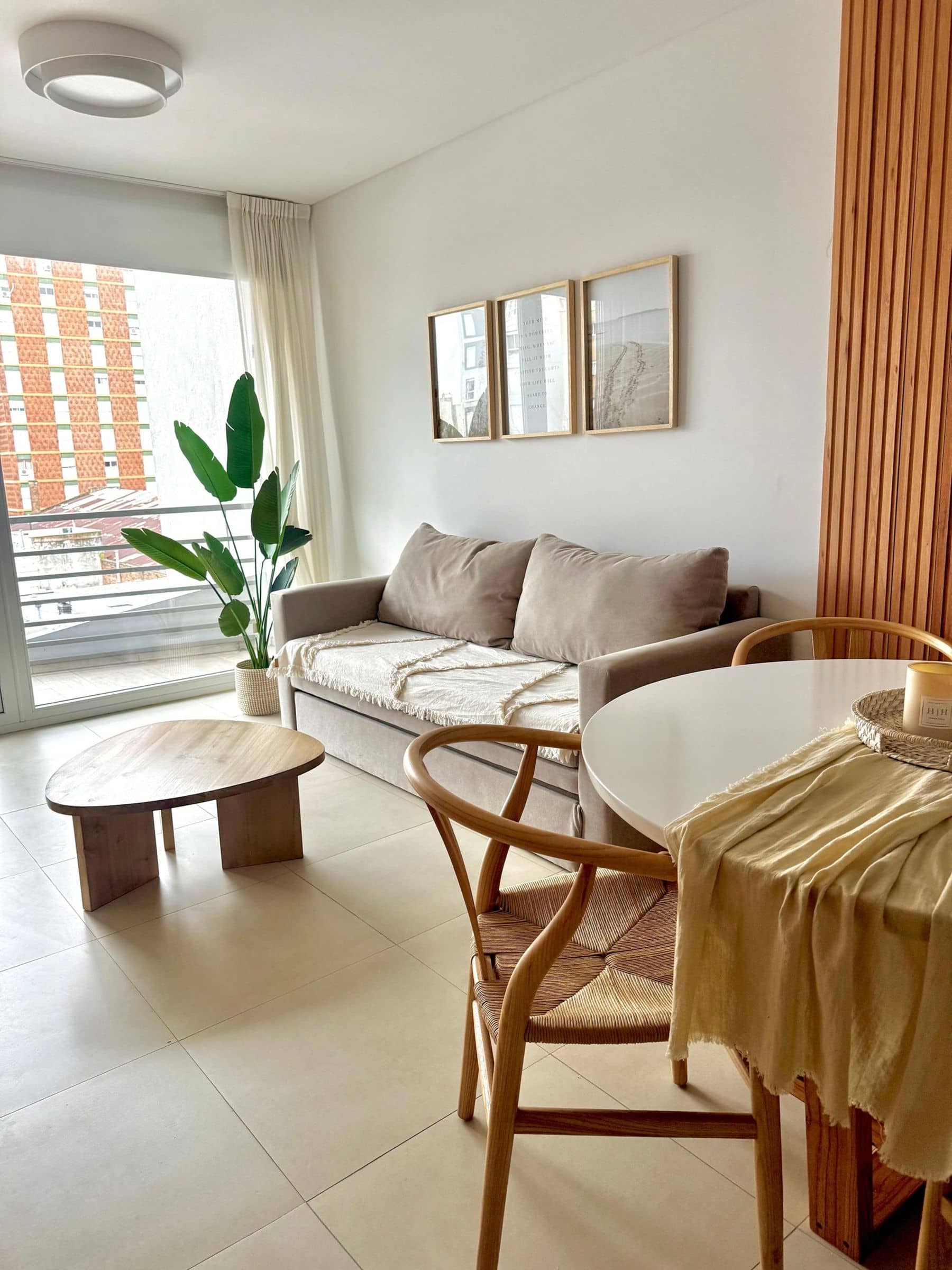 Living de Palazzo Tiberio 3 con ventanal, sillón gris, planta y cuadros